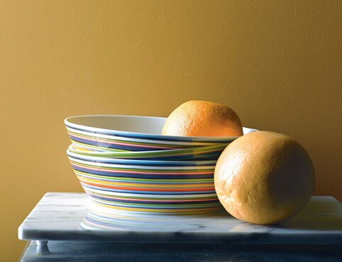 Dinner plates in variety of bright colours against yellow wall